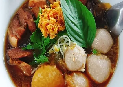 Kuay Tiew Moo Toon (Stewed Pork Noodle Soup) — Fresh rice noodles or egg noodles with stewed pork, pork balls, bean sprouts, green onion, fried garlic, and cilantro in five-spice stewed pork broth.