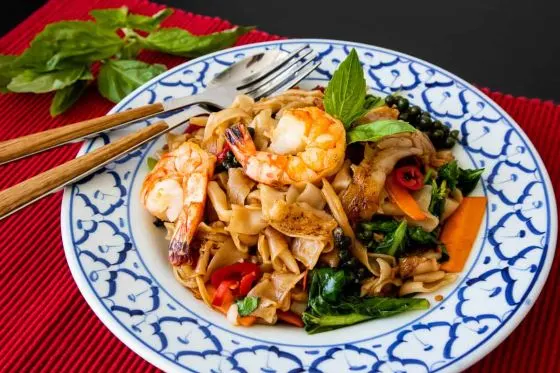 Kuay Tiew Pad Kee Mao — Stir-fried wide rice noodles with garlic, fresh chili, green beans, sweet peppers and Thai basil leaves.