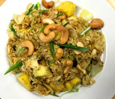 Khao Pad Sab Pa Rot (Pineapple Fried Rice) — Fried rice with egg, pineapple, sweet onions, raisins, curry powder, and cashew nuts.