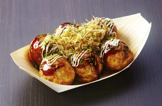 Takoyaki — A ball shaped Japanese snack made with dashi flavored batter filled with a few pieces of octopus, crispy scraps of tempura, green onions and pickled ginger. Served with takoyaki sauce, mayo and top with a sprinkle of seaweed and shavings of dried bonito.