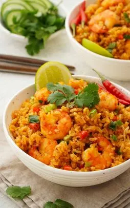 Khao Pad Tom Yum (Tom Yum Fried Rice) — Fried rice with tom yum sauce, Thai herbs, mushrooms, cherry tomatoes, and green onions.
