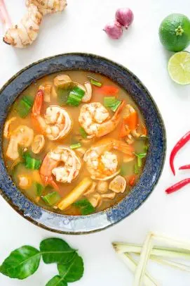 Tom Yum Goong — Traditional fiery tom yum soup with shrimp, mushrooms, tomatoes, fresh lemongrass, and kaffir lime leaves.
